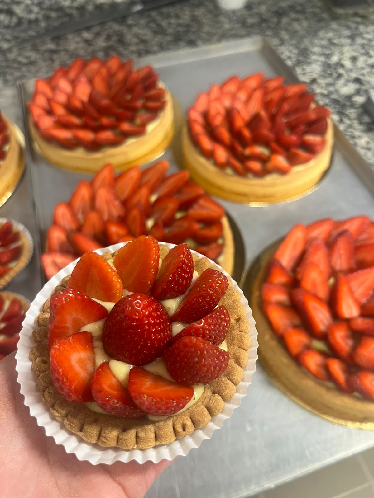 Tartelettes garnies de fraises fraîches taillées, présentées à la main