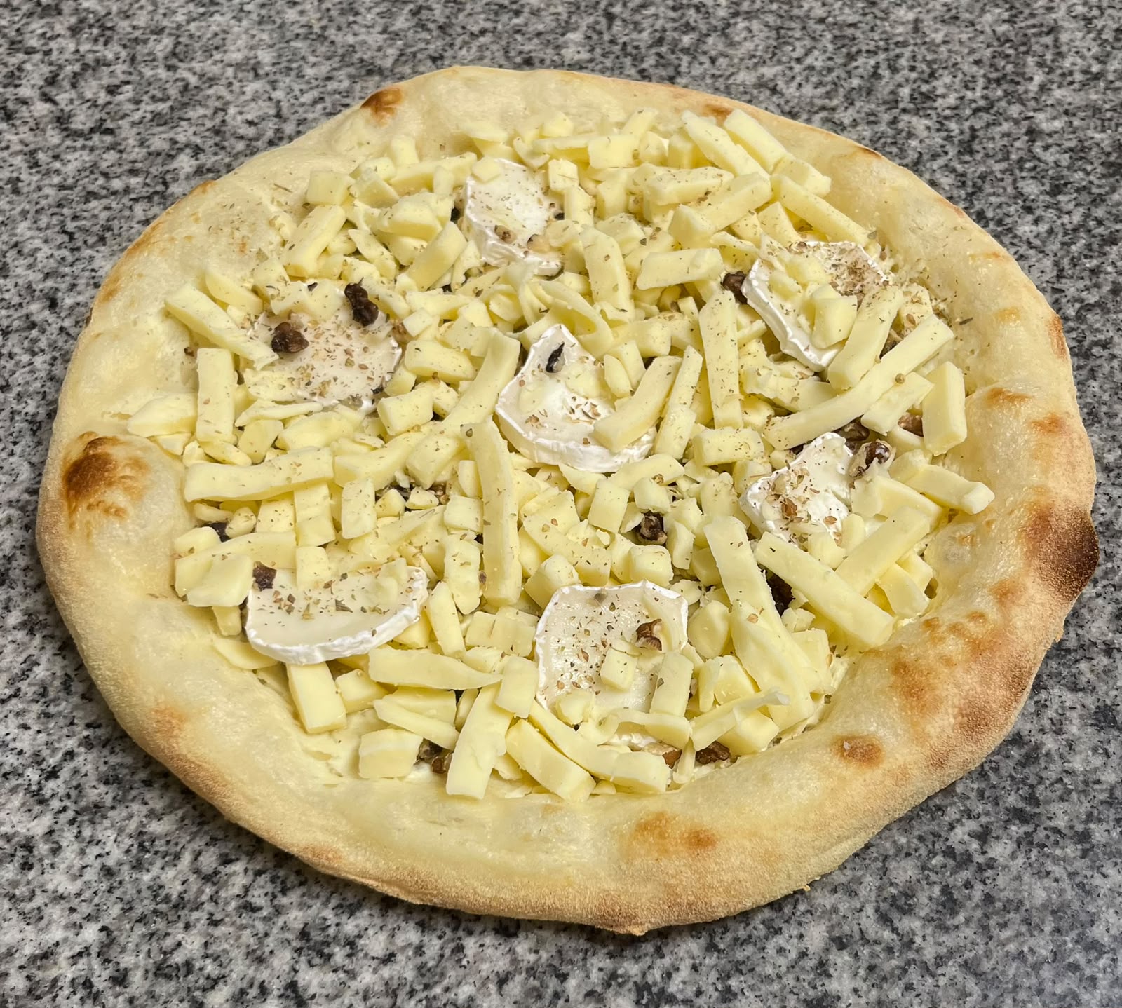 Pizza chèvre miel crue : rondelles de chèvre, noix et mozzarella râpée, garnie au fournil
