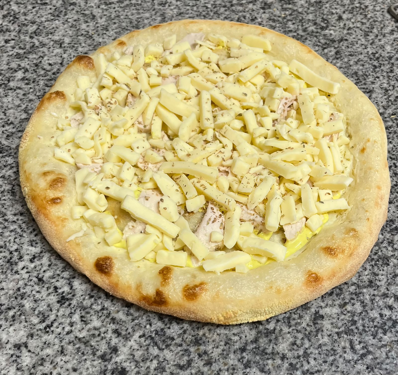Pizza poulet curry crue : poulet, sauce curry et mozzarella, garnie au fournil