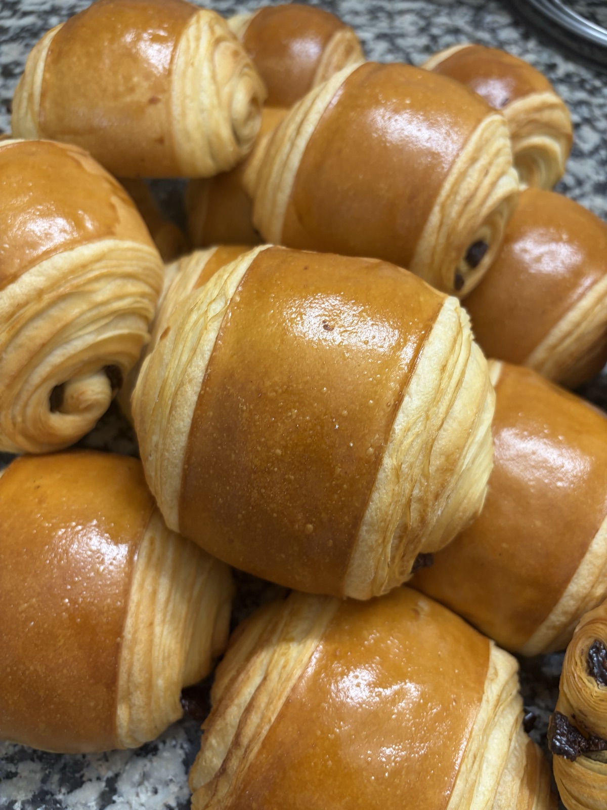 Pains au chocolat dorés et brillants, empilés, le chocolat visible aux extrémités